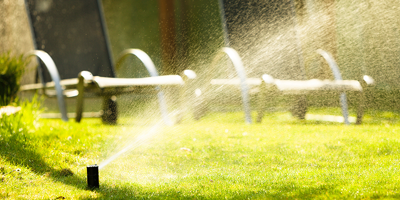 Gardening. Lawn sprinkler spraying water over green grass. Irrigation system - technique of watering in the garden.